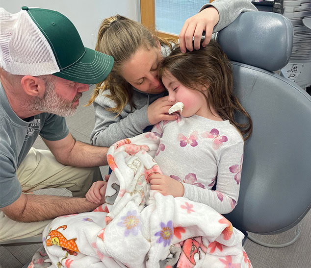 Sedation Dentistry | Child in dental chair being comforted by parents, gentle sedation.